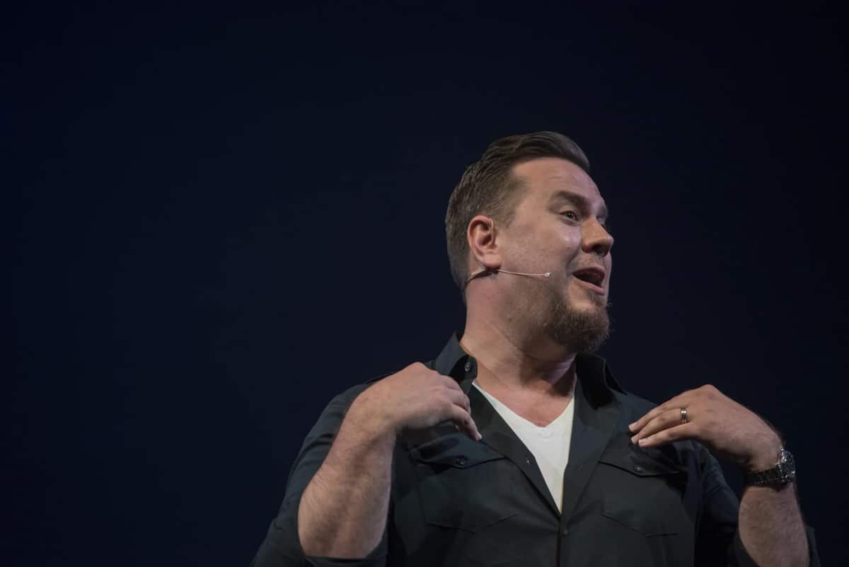 Cliff Johnson speaking onstage with a headset microphone